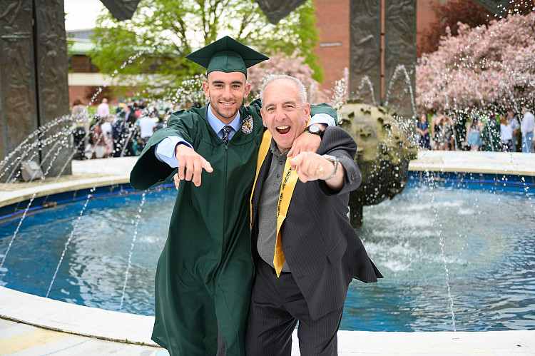 Brockport graduate celebrating with their father in front of the Special Olympics fountain