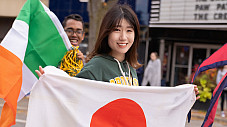 International student walking with a flag at the homecoming parade