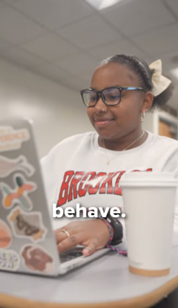 Winnie, a psychology major, sitting at a desk with her laptop opened up.