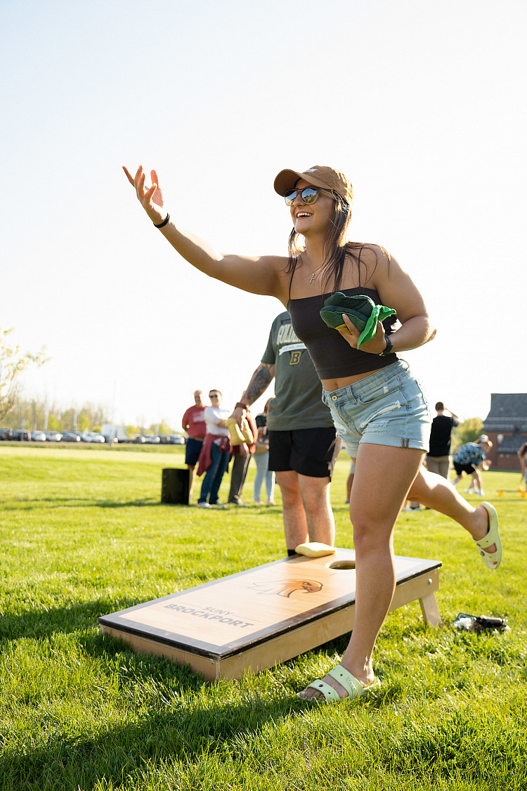 student throwing a sandbag during a corn hole game at the Almost Alum Block Party