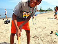 Child smiling at the camera while playing with sand at the beach