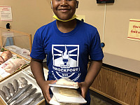 Child smiling at the camera holding packages of fish