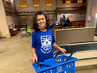 Child at a grocery store holding a basket