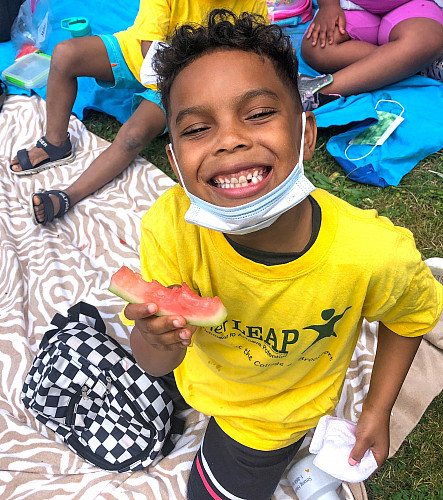 Child smiling and eating a watermelon
