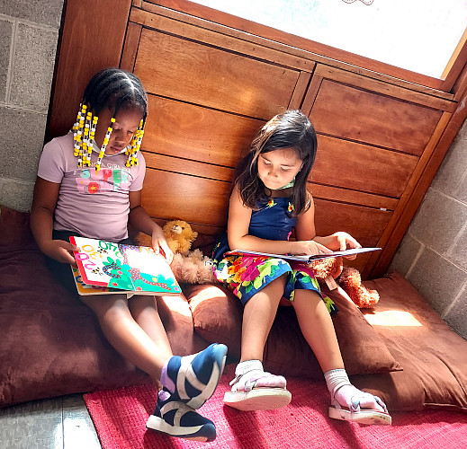 2 children sitting down in a classroom and reading