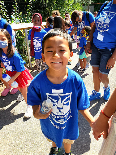 Child holding a water bottle and smiling at the camera