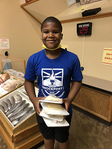 Child smiling at the camera holding packages of fish