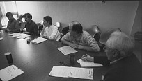 Black and white photo of people sitting at a conference room table.