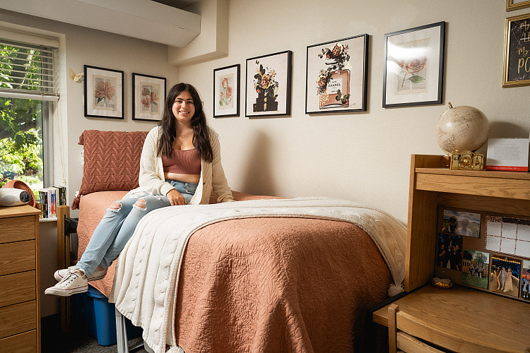freshman student poses on her bed as part of the real live rooms series