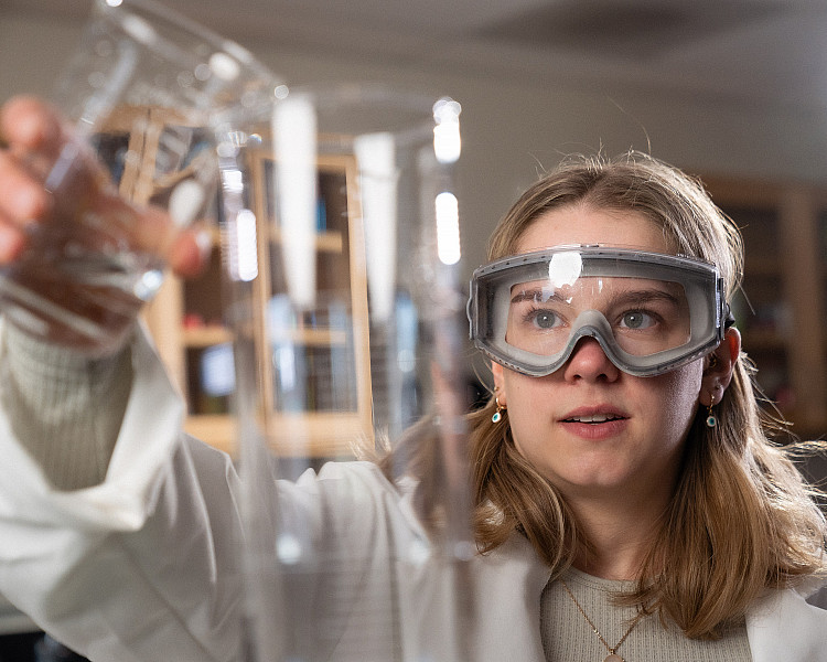 student pours liquid into a beaker 