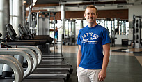 student stands in front of row of treadmills