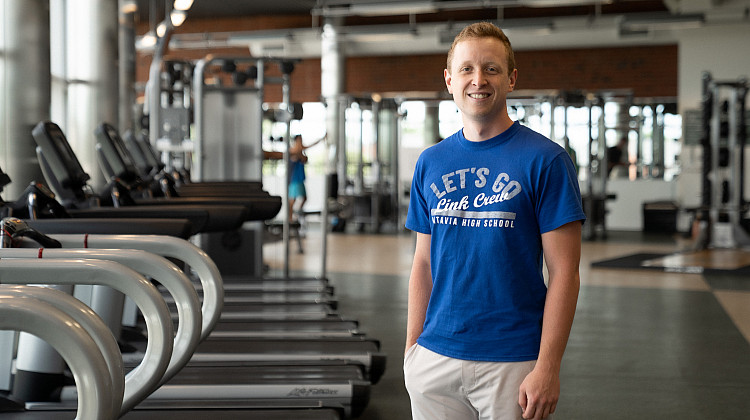 student stands in front of row of treadmills