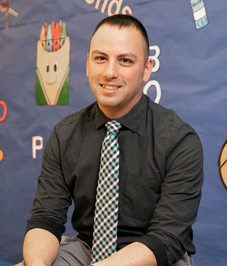 principal sits in front of children's artwork