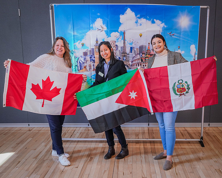Three individuals holding up flags at the International Festival during the Diversity Conference