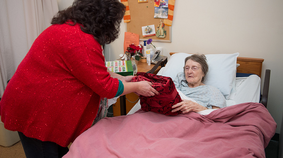 Someone caring for an elderly person in a bed