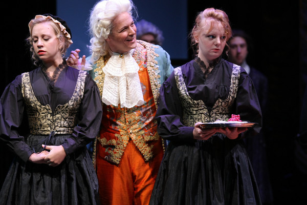 Geva actor in early colonial clothes in between two actresses in colonial clothes that look unhap...