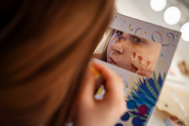 Student putting on makeup backstage