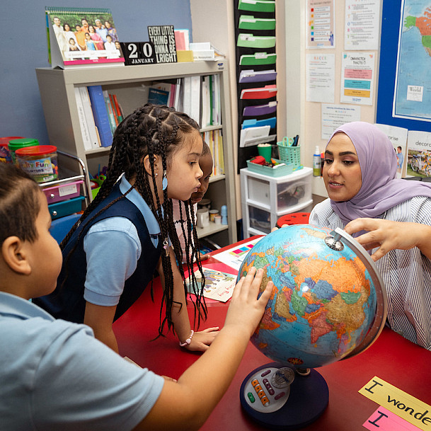 Teacher and students exploring the globe.