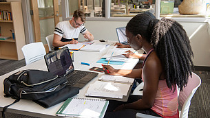 Students studying at a table with notebooks and laptops in the Academic Success Center