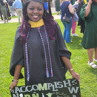 Aishia Wall standing outside the SERC on graduate day in her academic regalia