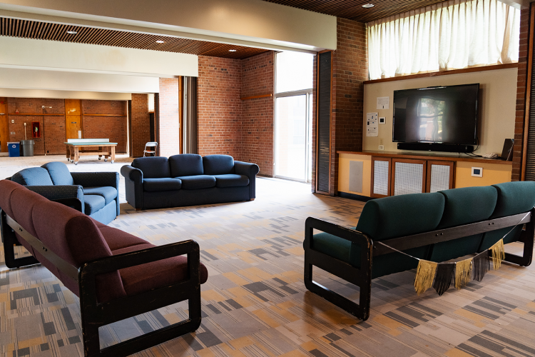 Close up of main lounge area of a common room with 4 couches and a wall-mounted TV