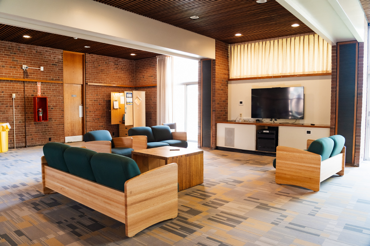 Close up of a smaller lounge area of a common room with 3 couches, an armchair, coffee table, and a wall mounted TV