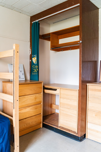 Close up of a small dresser, closet space, and another dresser in a corner of a 4 person suite