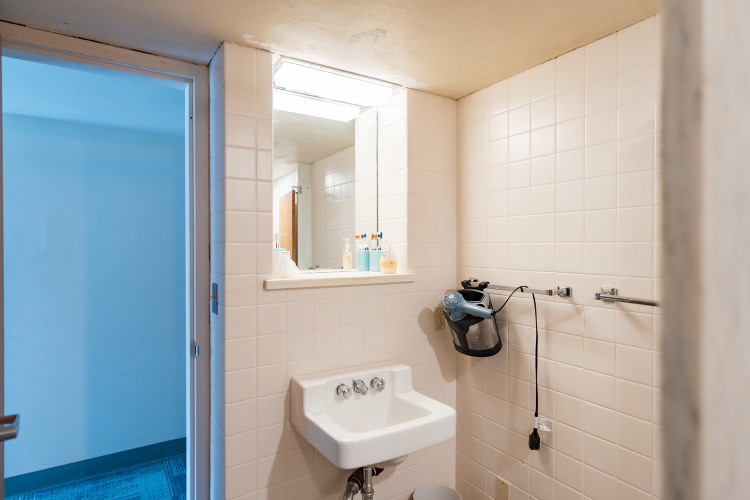 Close up of a vanity in the bathroom of a 4 person suite with a mirror, sink, and towel racks