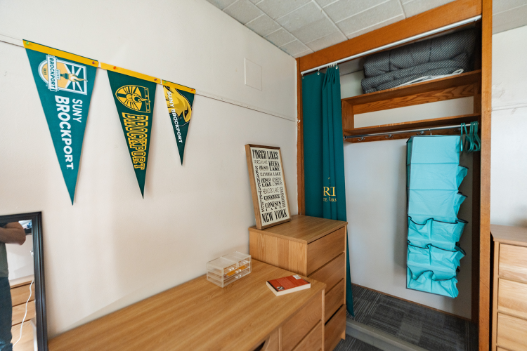 Close up of the decorated back wall of a bedroom with a desk, dresser, and a closet space in the corner