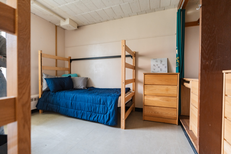 Entrance view of a bedroom with a bed and dresser against the back wall and a closet space to the right
