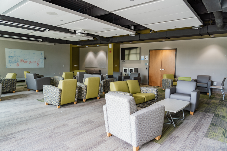 Eagle Hall main lobby with chairs and tables, with whiteboards and a TV mounted on the walls