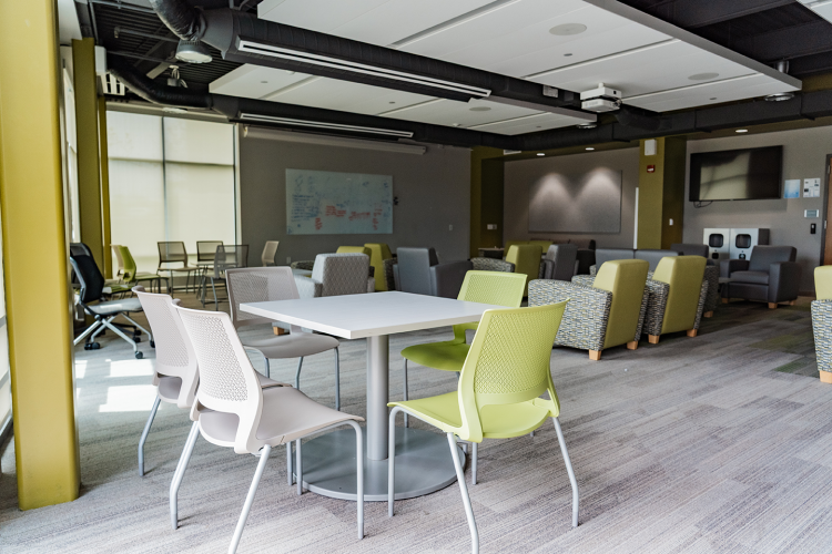 Close up of a table and chairs with more chairs and tables in the background of the Eagle Hall main lobby