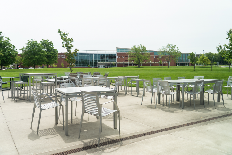 Outside view of the patio outside Eagle Hall with tables, chairs, and the SERC building in the background
