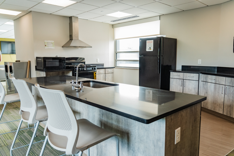 Kitchen area with a microwave, stove, fridge next to countertops, and an island with a sink