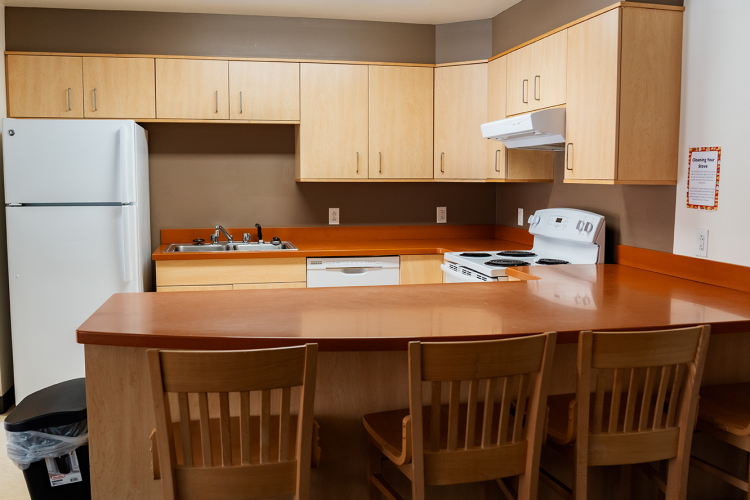 Side view of the U-shaped layout kitchen with a fridge, sink, dishwasher, and stove