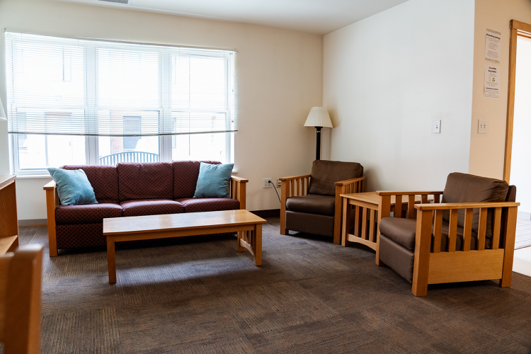 Angled view of a living room with a couch, 2 lounge chairs, and a coffee table
