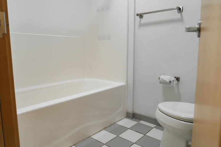 Entrance view of a bathroom with a full-sized bathtub, towel rack, and toilet