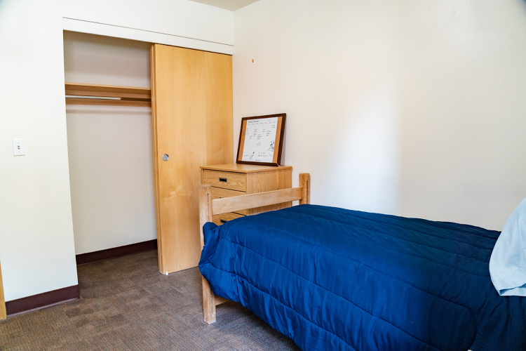 Angled view of a bedroom with a closet space, dresser, and bed