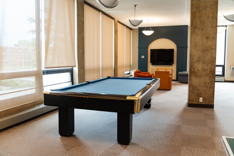 Wide view of a lobby with a pool table, lounge chairs, and a wall-mounted TV