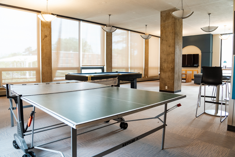 Entrance view of a lobby with a ping pong table, pool table, lounge chairs, and a wall-mounted TV