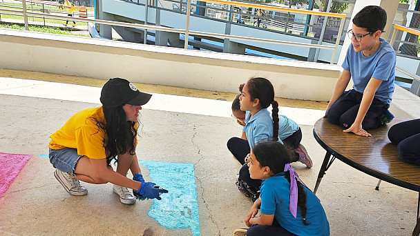 Guerro painting the pavement while students watch